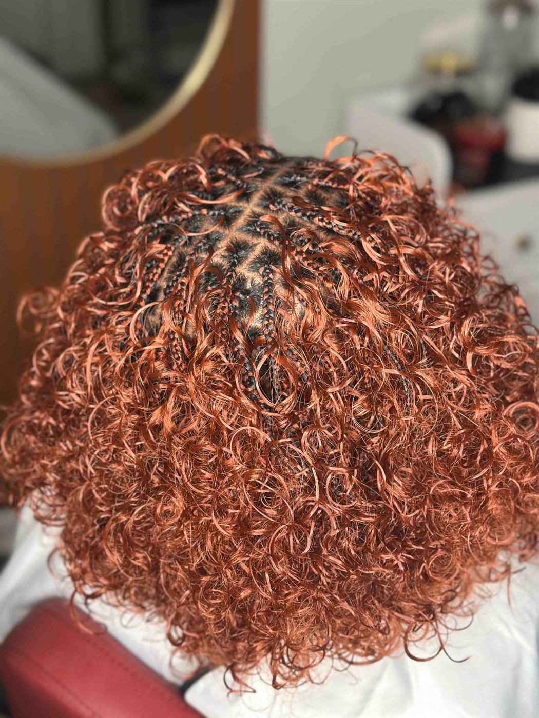 Copper Italian braids from behind in the salon chair, a gold-framed mirror beside